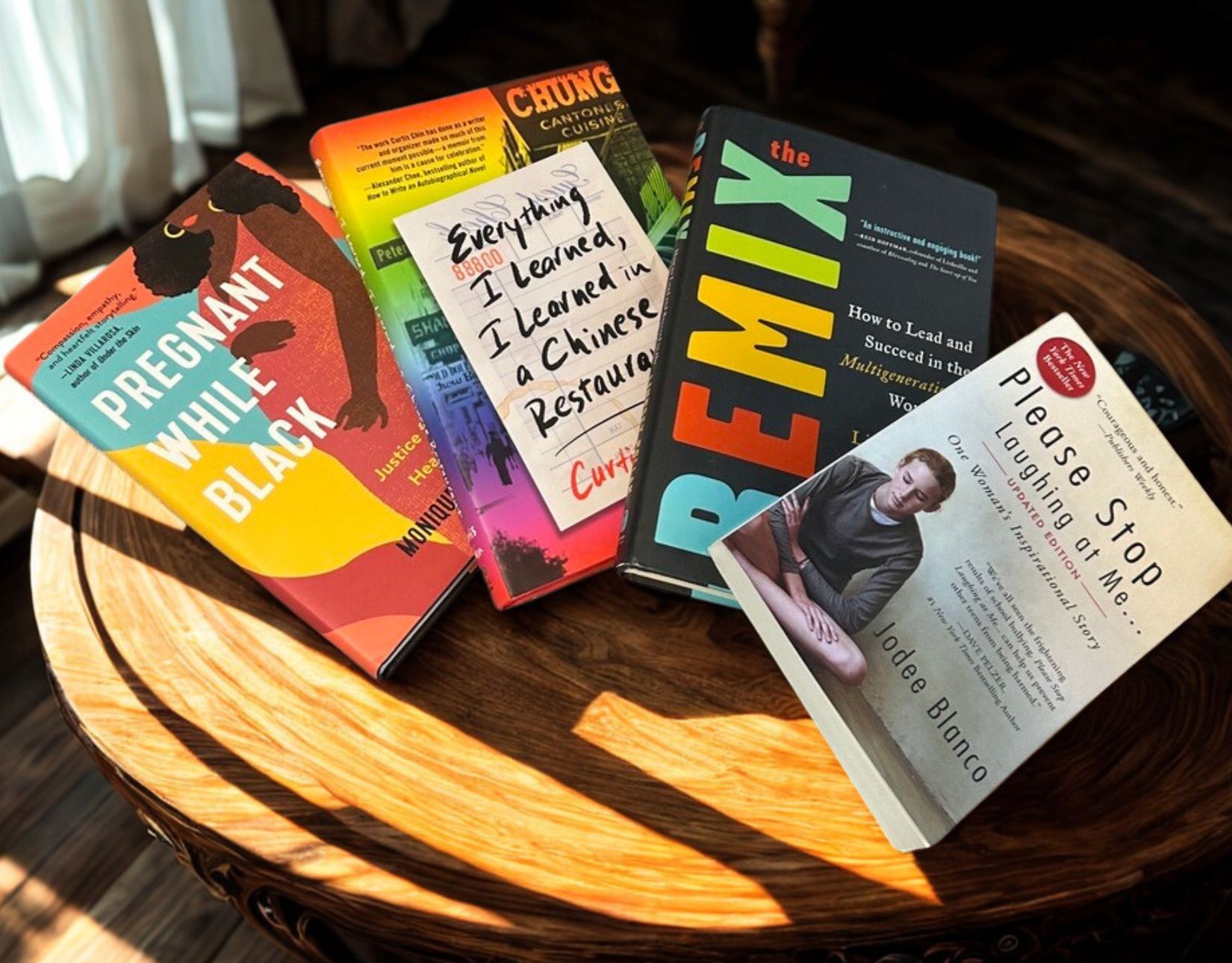 The books Pregnant While Black, Everything I Learned I Learned in a Chinese Restaurant, The Remix, and Please Stop Laughing at Me displayed on a table.