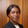 Frances Amaefuna wearing a black blazer and light peach blouse with her hair pulled back in formal cropped photo.